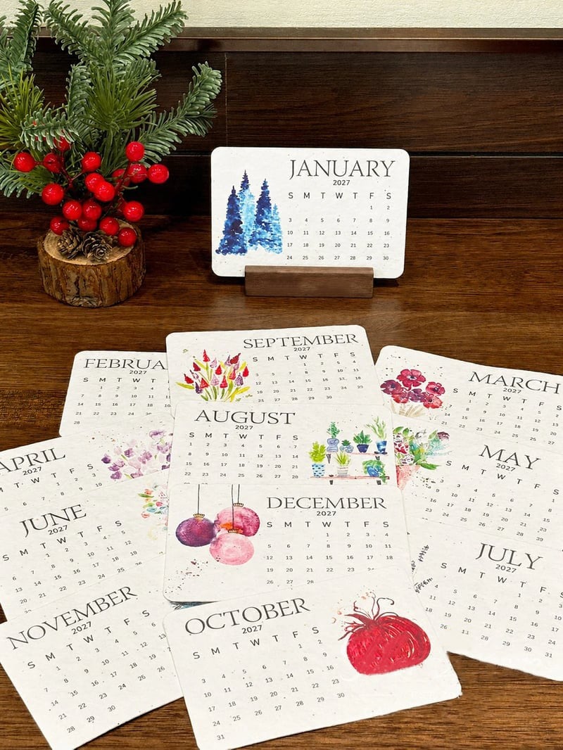 2027 plantable calendar cards displayed on wooden tabletop with seasonal decorative greenery