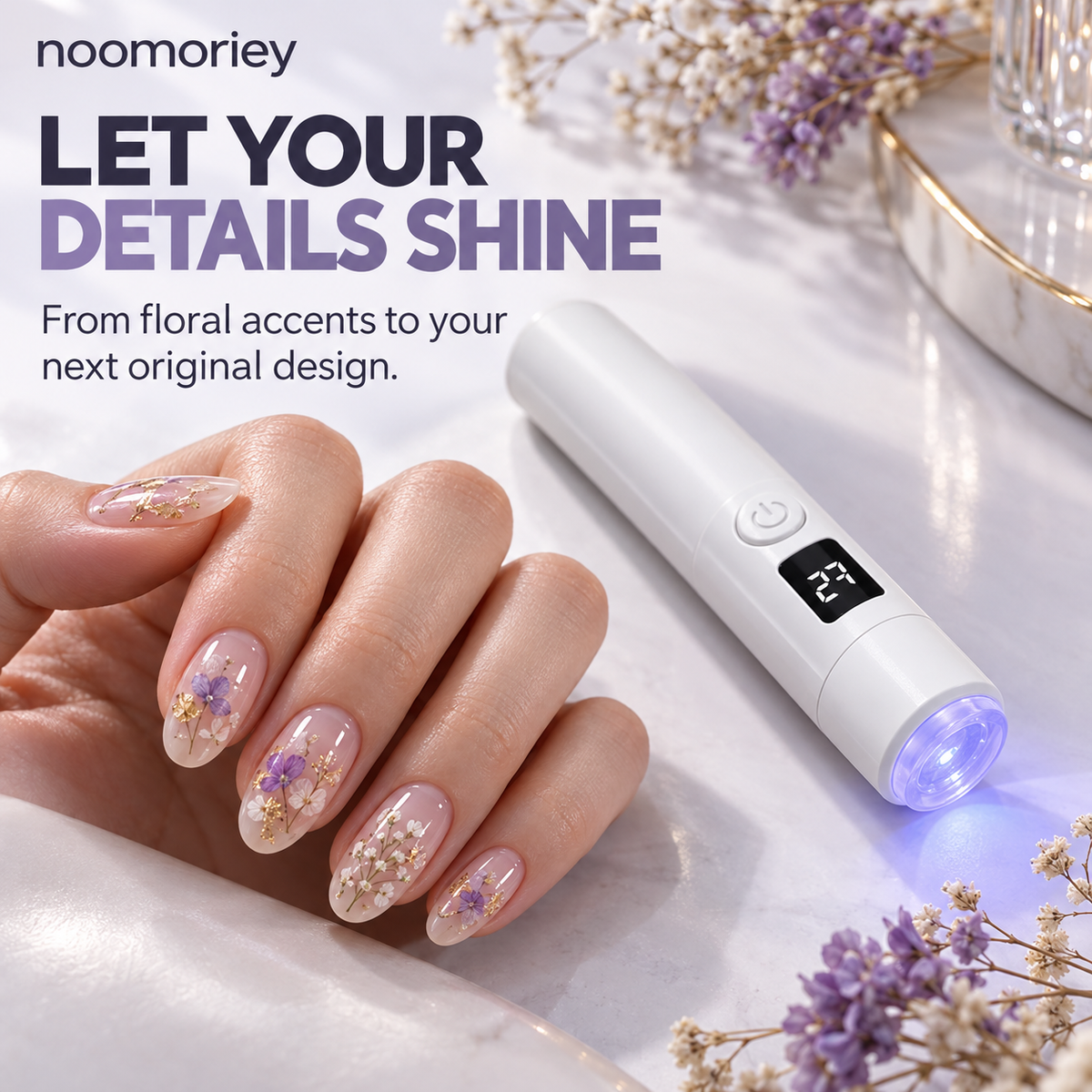 Finished floral manicure beside handheld nail lamp